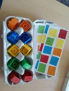 an open box filled with different colored legos on top of a wooden table next to a pair of scissors