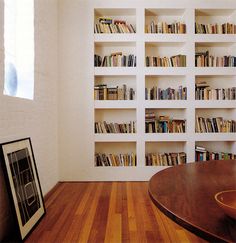 an empty room with bookshelves and a wooden table in front of the window