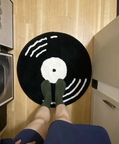 a person standing in front of a black and white rug with an image of a record on it