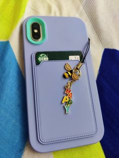 a cell phone case with a keychain attached to it on a colorful blanket