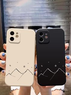 two people holding up cell phones with mountains on them