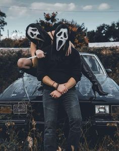 two people wearing masks sitting on top of a car