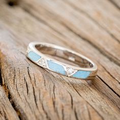 a silver ring with blue and white stones on top of wooden planked flooring