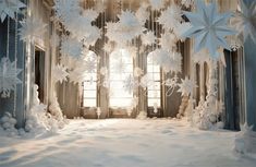 snowflakes hanging from the ceiling in front of a window with curtains and windowsills