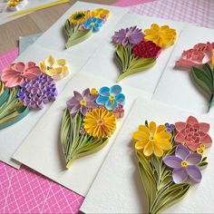 four cards with flowers on them sitting on a table