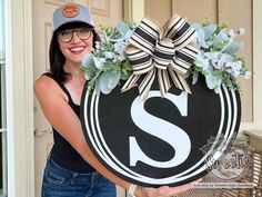 a woman holding up a sign with the letter s on it and flowers in front of her