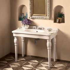 a white sink sitting under a mirror next to a wall mounted faucet in a bathroom