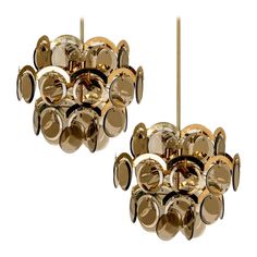 two gold chandeliers hanging from the ceiling, each with different sized discs on them