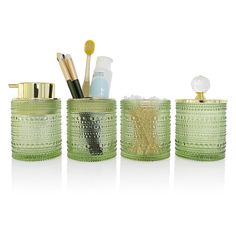 three green glass containers with toothbrushes and other items