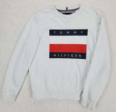 Tommy Hilfiger Sweatshirt  Graphic Flag Logo White Size Medium  Item is pre-owned with no noted flaws.  Sweatshirt shows normal wear.  Band around waist and wrist are rippled. Item has been laundered and still holds a previous fragrance. Please take measurements into consideration for clothing fit.        Approximate flat lay measurements:          Shoulder:  17.5"           Pit to pit:  21.5"           Sleeve length:  25.5"           Length:  25" Please view photos of the item. I am available f White Cotton Logo Sweater, White Sporty Sweater With Logo, Sporty White Sweater With Logo, Tommy Hilfiger Logo Print Sweatshirt For Streetwear, Tommy Hilfiger Logo Print Sweatshirt For Fall, Sporty Tommy Hilfiger Sweatshirt With Logo Print, Tommy Hilfiger Letter Print Sweatshirt For Winter, Tommy Hilfiger Sporty Sweatshirt With Logo Print, Tommy Hilfiger Letter Print Winter Sweatshirt