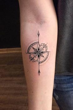 a black and white compass tattoo on the right leg, with an arrow in the middle