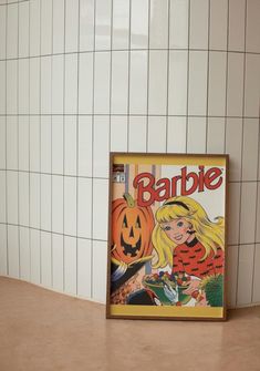 a barbie magazine cover sitting on top of a counter next to a tiled bathroom wall