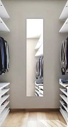 an empty walk in closet with white shelving and clothes hanging on the shelves,