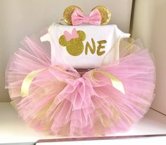 a pink and gold minnie mouse tutu with a one on it's top