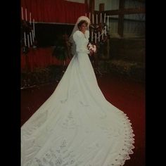 an old photo of a woman in a wedding dress standing next to a red curtain