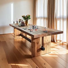 a wooden table sitting on top of a hard wood floor next to a vase filled with flowers