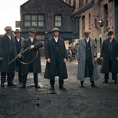 several men in coats and hats are standing outside