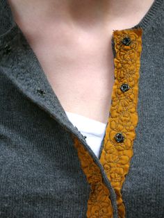 a close up of a person wearing a gray shirt and yellow tie with black buttons