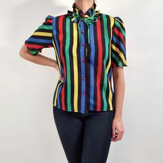 Beautiful vintage blouse in black, blue, red, green and yellow stripes with a frilly collar. It has a simple, straight shape, puffed short sleeves, collar ties and six, red buttons fastening. It is made from lightweight, slightly see-through fabric. Perfect, cheerful blouse for everyday or special occasions. No brand label. 100% polyester. No size label, would fit Small to Medium sizes. Measurements when laid flat are: Pit to pit: 50cm Waist: 80cm Shoulders length: 38cm Length: 60cm. Great condition, apart from one pulled thread on the front. Please see photo. B. Short Sleeve Vertical Stripes Blouse For Work, Short Sleeve Vertical Stripe Workwear Blouse, Multicolor Short Sleeve Top With Striped Collar, Multicolor Short Sleeve Tops With Striped Collar, Multicolor Collar Blouse For Work, Multicolor Short Sleeve Work Shirt, Multicolor Short Sleeve Tops For Work, Retro Fitted Tie-neck Top, Retro Multicolor Blouse For Work