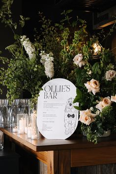 flowers and candles sit on a table with a sign that says ollie's bar