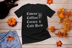 "This \"Cold Brew Coffins and Covens\" goth Halloween Tee is great for witchy fans of all things spooky, cold brew coffee & Covens. Design features a distressed vintage text that reads Cold Brew Coffins and Covens. Great Tee to wear during Halloween season. This witchy tee \"Covens Coffins Curses and Cold Brew\" is perfect for Halloween, Watching Horror Movies and being spooky. Also makes a great gift for Christmas, Xmas, or any Spooky occasion. If you're a witch and a coffee lover than this design is for you! *PROCESSING TIMES, SHIPPING & OTHER INFO* * Our Processing time is 1-2 business days ( Note: Times may vary during the Holiday season) * Please Review Size Chart before ordering. For a more loose fit please order a size up. * Professionally Printed using a DTG (Direct To Garment) Pri Fitted Gothic T-shirt For Fall, Gothic Letter Print Tops For Fall, Alternative Style Top For Halloween Costume Party, Alternative Halloween Cosplay T-shirt, Halloween Cosplay Alternative Style T-shirt, Alternative Style Halloween Cosplay T-shirt, Fall Gothic T-shirt With Short Sleeves, Gothic Halloween Cosplay T-shirt, Gothic Cosplay T-shirt For Halloween