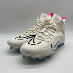 a pair of white and blue nike cleats on a gray background with pink accents