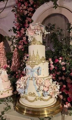 three tiered wedding cake sitting on top of a table next to pink and white flowers