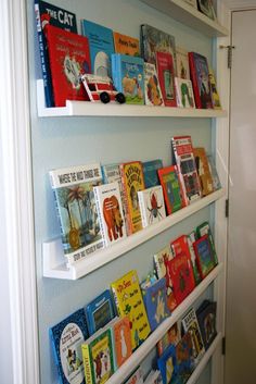 the books are lined up on the wall behind the shelves in the children's room