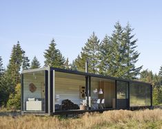 a small house in the middle of a field with trees around it and grass on the ground