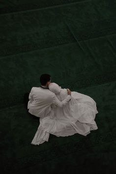 a woman in white dress sitting on the ground with her back turned to the camera