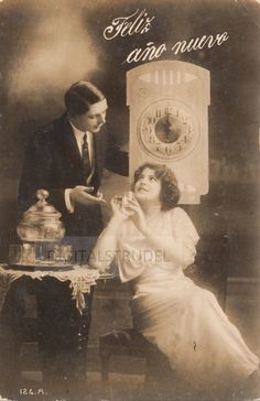 an old black and white photo of a woman sitting at a table next to a man