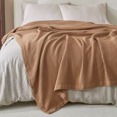 a bed with a brown blanket and white pillows