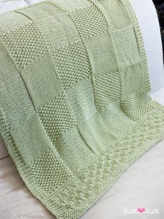 a green knitted blanket sitting on top of a bed