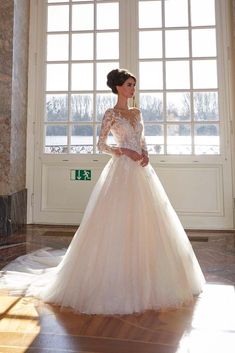 a woman in a wedding dress standing by a window