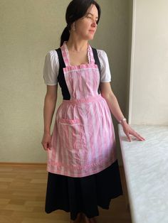 a woman in pink and black dress standing next to a white counter with her hands out