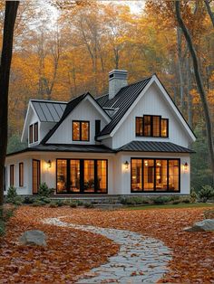 a white house with lots of windows in the front yard and leaves on the ground