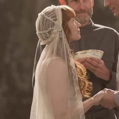 a man and woman standing next to each other in front of a white veil on their head