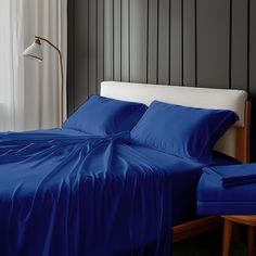 a bed with blue sheets and pillows in a room