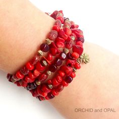 a close up of a person's arm wearing bracelets with red beads and charms