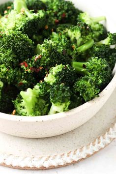 a white bowl filled with broccoli on top of a table