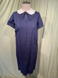 This is a cute vintage dress from the 60s. Label reads, Toni Lynn. Tagged a size 12. The bust measures 38", waist 40", see measurements below. I believe this is a maternity dress as the front button panel opens to reveal a generous pleat, to grow as you grow. Buttoned up it is a shift dress.  Made of blue cotton with a slight weave texture.  The dress is not lined.  It is short sleeve with a white Peter Pan style collar trimmed with a ball trim. Under the collar is a large bow. The buttons go all the way down the front & are covered in matching fabric. The dress slips over the head. The dress is in very good condition, no damage. No soil or stains.  Although this is a maternity dress, it is also a very nice shift dress! Charming! Measurements were taken with the garment lying flat. If you 90s Maternity Dress, Classic Blue Dress For Vintage Fashion, Blue Knee-length Vintage Dress 1950s Style, Vintage Blue A-line Midi Dress, Blue Knee-length 1950s Vintage Dress, Blue 1950s Style Knee-length Vintage Dress, Blue Vintage A-line Midi Dress, Fitted Retro Dress With Doll Collar, Retro Fitted Dress With Doll Collar