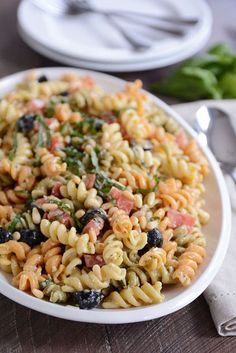 a pasta salad with tomatoes, olives and spinach