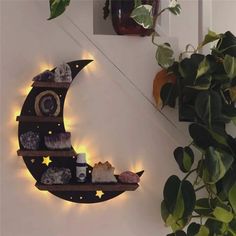 the moon shelf is lit up with candles and rocks on it, along with some plants