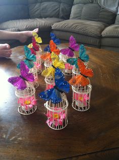 colorful butterflies in cages sitting on a table next to a person's feet and couch