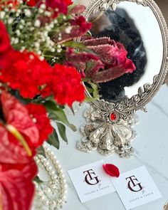 a mirror and flowers on a table with place cards in front of the mirror that says, i do not know what this is