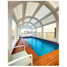 an indoor swimming pool in the middle of a room with white walls and wooden floors