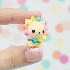 a hand holding a tiny toy animal on it's finger with polka dots in the background