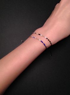 a woman's arm with three bracelets on it, one is black and the other is blue