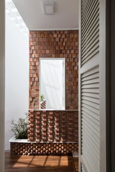 an open door leading to a room with brick walls and wooden floors, along with a plant