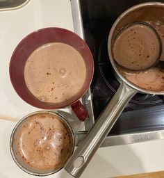 there are two pots on the stove with hot chocolate in them, and one is empty